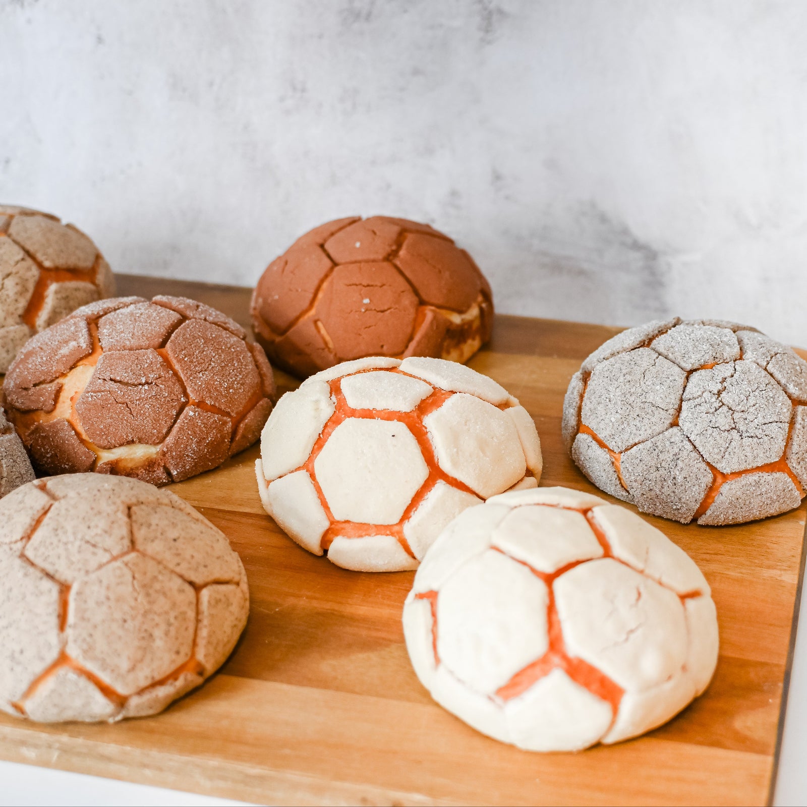 Wooden board with soccer ball-shaped conchas on a marble background